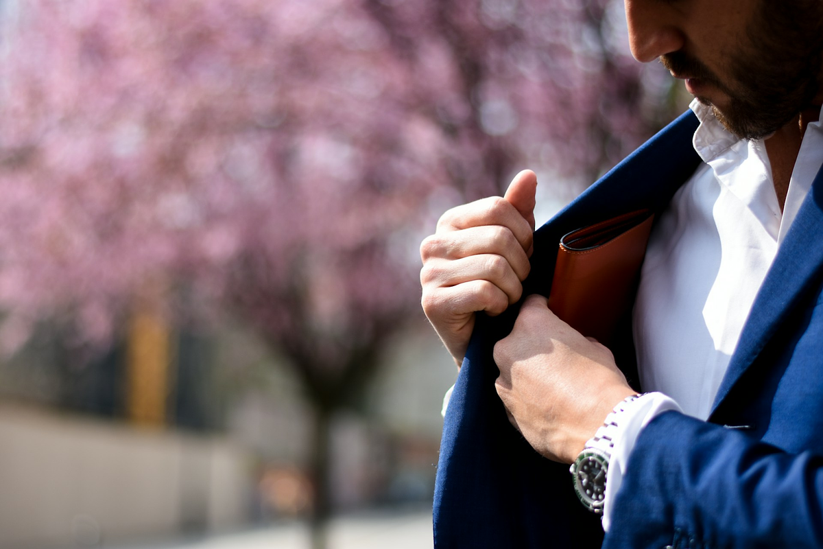 man putting wallet on suit pocket